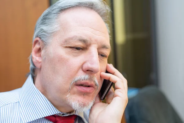 彼のオフィスの携帯電話で話している上級ビジネスマンの肖像画 — ストック写真