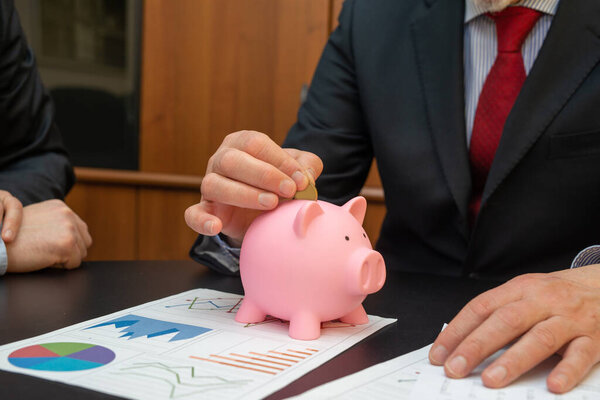 Businessman putting money in the piggy bank, money save concept