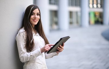 Gülümseyen iş kadını dijital tablet kullanıyor.