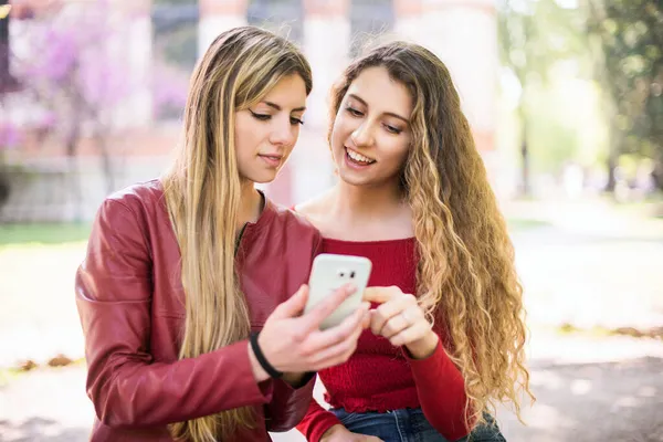 Dışarıda cep telefonu kullanan gülümseyen kadınlar.