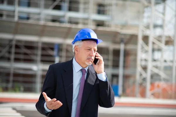 工事現場前の携帯電話で話す怒っている建築家マネージャー — ストック写真