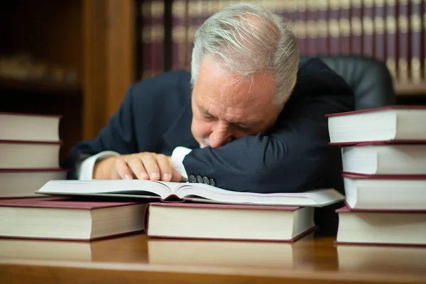 多くの本に囲まれた眠そうなビジネスマン弁護士 — ストック写真