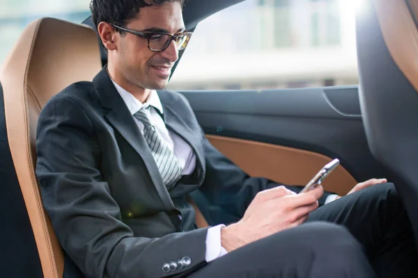 商人在汽车后座上使用他的智能手机 — 图库照片