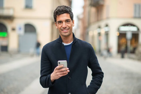 Jonge Glimlachende Man Met Zijn Mobiele Telefoon Een Stedelijke Omgeving — Stockfoto