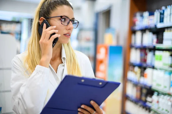 Női Gyógyszerész Beszél Telefonon Egy Vásárlóval Boltjában — Stock Fotó
