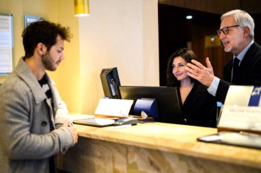 Müşteri otel resepsiyonuna kayıt yaptırıyor.