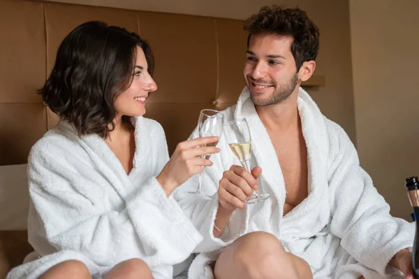 年轻夫妇在卧室里品着一杯起泡的葡萄酒 — 图库照片