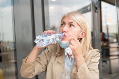 Coronavirus salgını sırasında bir şişe su içen kadın.
