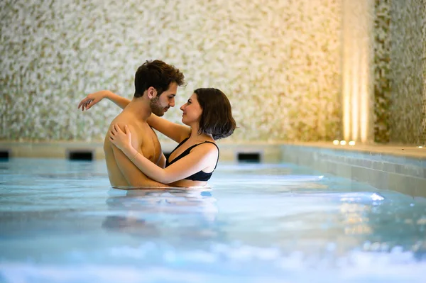 在游泳池温泉中心酒店拥抱的年轻夫妇 — 图库照片