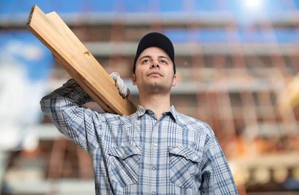 Stolarz Trzymający Drewnianą Deskę Przed Placem Budowy — Zdjęcie stockowe