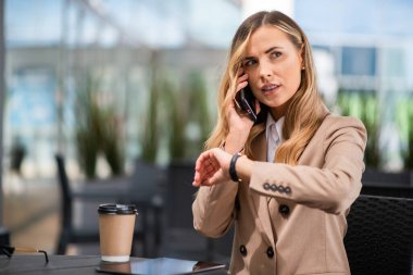 Molada telefonla konuşan ve saatini kontrol eden genç bir kadının portresi.