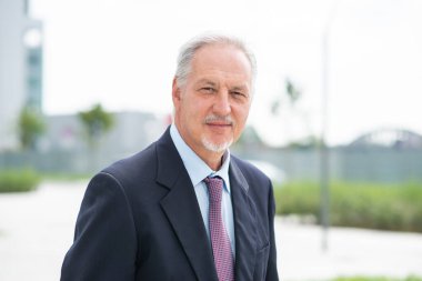 Modern bir şehirde yürüyen kendinden emin bir işadamının portresi.