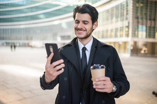 Fešák Elegantní Oblečený Muž Pomocí Svého Smartphonu Drží Šálek Kávy — Stock fotografie