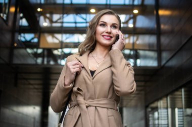 İş kadını yürürken telefonda konuşuyor.