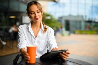 Kahve molasında genç bir iş kadını, kameraya gülümsüyor.