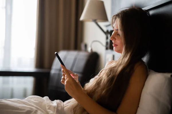 Молодая Сексуальная Женщина Расслабляется Своим Смартфоном Постели — стоковое фото
