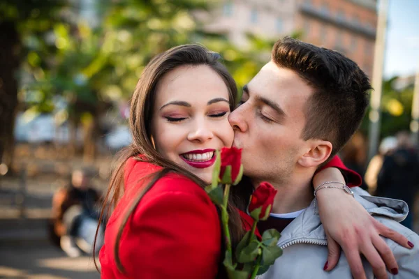 Young man giving flowers and kissing his girlfriend