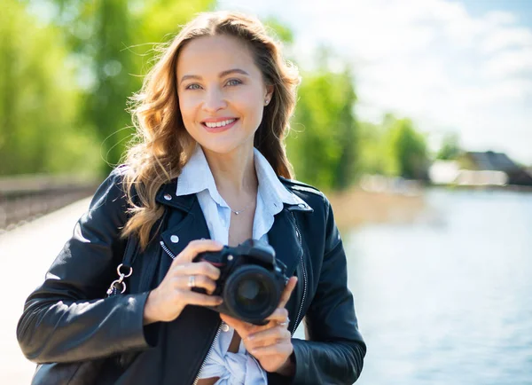 反射カメラを屋外に持っている若い笑顔の女性 — ストック写真