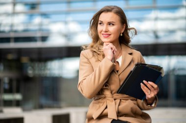 Dijital tablet kullanan gülümseyen iş kadını bankta oturuyor.