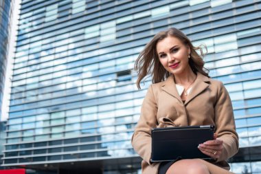 İş kadını dışarıda otururken tabletini kullanıyor.