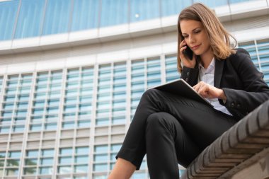 İş kadını tabletini kullanırken telefonda konuşuyor.