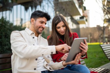 Dışarıda tablet kullanan genç bir çift.