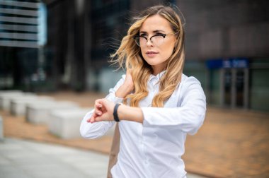 Kendine güveni tam bir bayan yönetici. Saati kontrol ediyor.