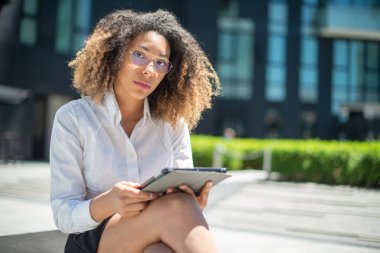 Afro-Amerikalı iş kadını iş ortamında dijital tabletini açık havada kullanıyor.