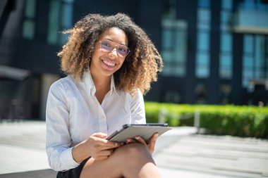 Afro-Amerikalı iş kadını iş ortamında dijital tabletini açık havada kullanıyor
