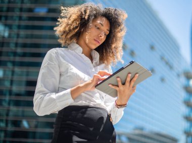 Afro-Amerikalı iş kadını iş ortamında dijital tabletini açık havada kullanıyor