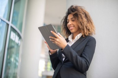 Afro-Amerikalı iş kadını iş ortamında dijital tabletini açık havada kullanıyor.