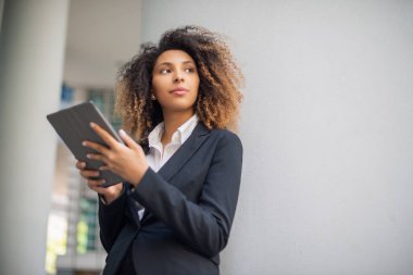 Afro-Amerikalı iş kadını iş ortamında dijital tabletini açık havada kullanıyor.