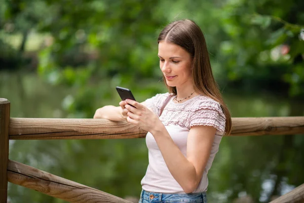 年轻女子在公园里使用智能手机 — 图库照片