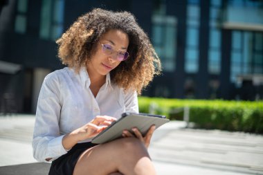 Afro-Amerikalı iş kadını iş ortamında dijital tabletini açık havada kullanıyor