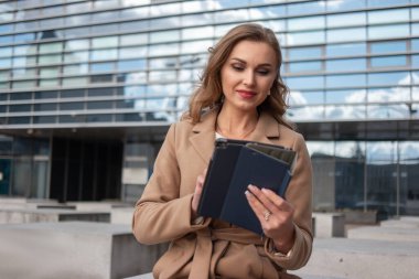 İş kadını dışarıda otururken tabletini kullanıyor.