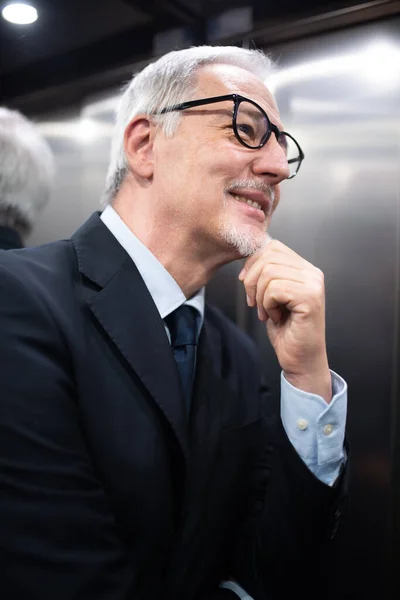 Smiling senior businessman inside an elevator