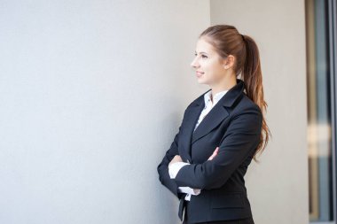 Duvarın yanında gülümseyen genç bir iş kadınının portresi