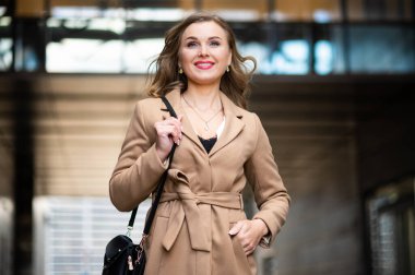 Dışarıda çantasını tutan bir kadın var.