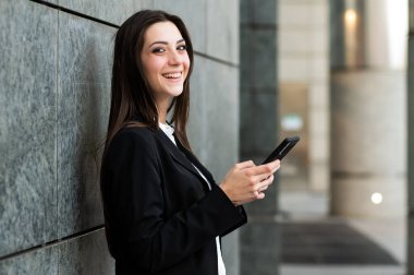 Güzel genç bayan yönetici dışarıda akıllı telefonunu kullanıyor.