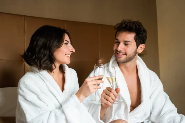 年轻夫妇在卧室里品着一杯起泡的葡萄酒 — 图库照片