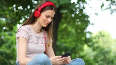 Parkta bankta oturmuş müzik dinleyen bir kadın.