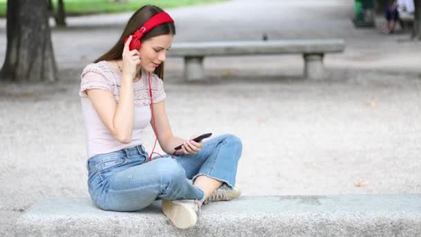 Mujer Escuchando Música Sentada Banco Parque — Vídeo de stock