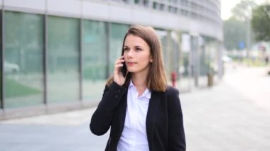 Telefonda yürüyen ve konuşan genç bir kadının portresi.