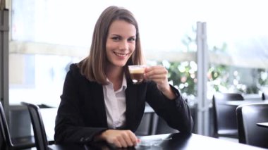 Kendine güvenen genç bayan müdür kafede kahve içiyor. 