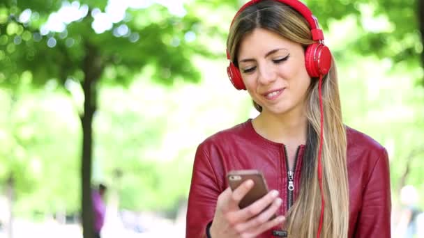 Mujer Escuchando Música Sentada Banco Parque — Vídeos de Stock