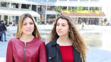 İki kadın arkadaş modern bir şehirde yürüyüş ve konuşuyor