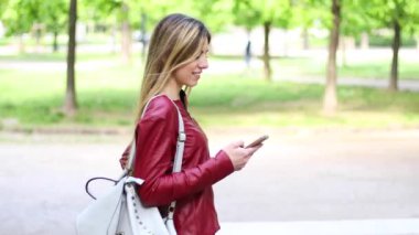 Akıllı telefonunu kullanırken parkta yürüyen kadın