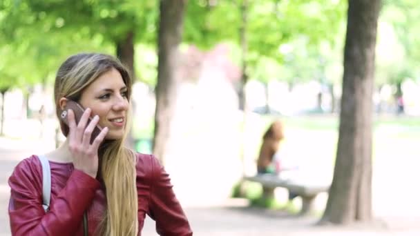야외에서 미소짓는 학생에게 전화로 말하는 — 비디오