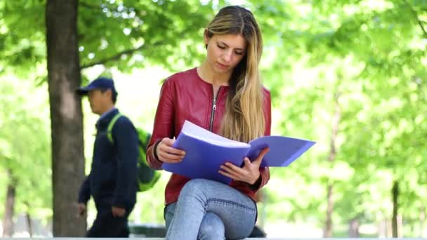 美丽的女大学生在公园的长椅上看书 — 图库视频影像