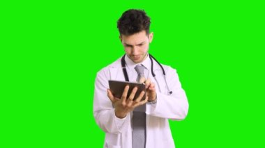 Ciddi bir doktor yeşil ekran krom anahtar arka planında izole edilmiş bir tableti tarıyor